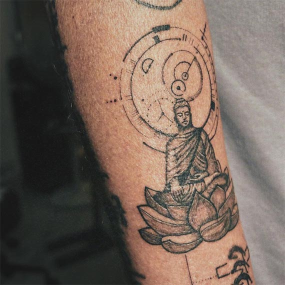 buddha with bhumisparsha mudra on lotus and fineline geometry tattoo male forearm