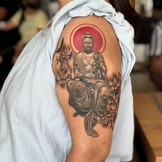 sculpture gautam buddha with flowers and red circle at back tattoo design female bicep
