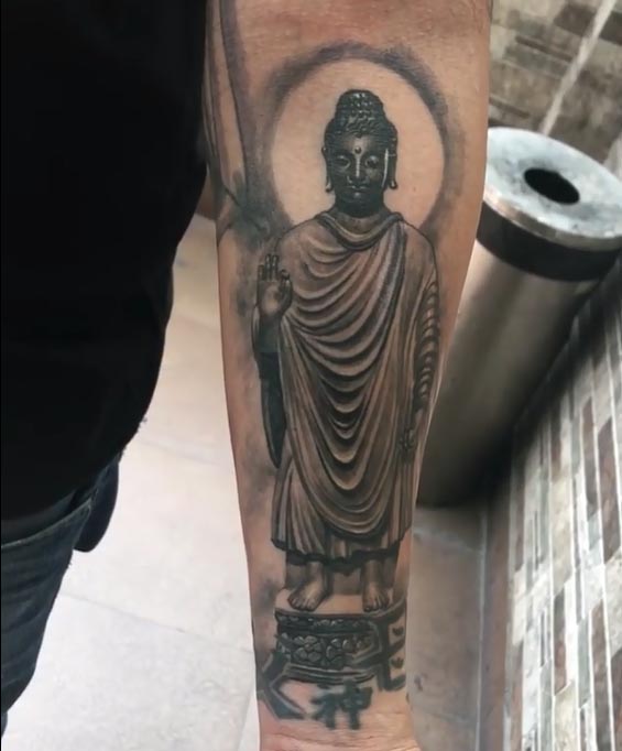 standing buddha on wooden stool tattoo design male forearm