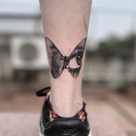 butterfly with one eye on a wing tattoo female leg calf
