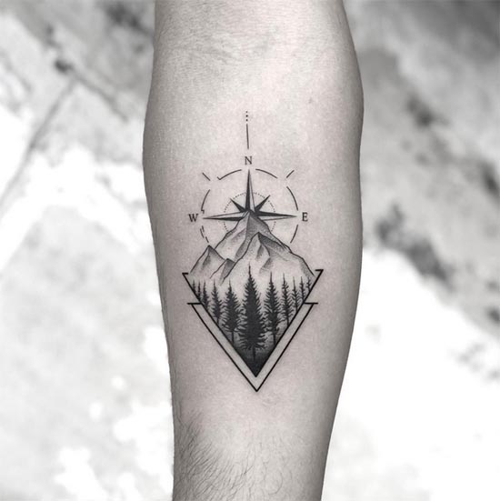 compass rose mountain peaks pine forest trees wilderness landscape geometric triangle tattoo male forearm