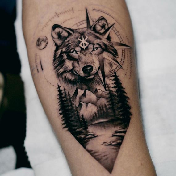 wolf head compass mountains pine trees forest landscape winding path geometric circles tattoo male forearm
