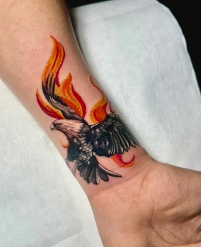 eagle with fire strokes from behind tattoo design male arm wrist