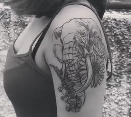 elephant head with flowers tattoo woman bicep