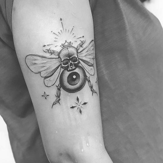 bee-skull-as-head-with-crown-eye-as-body-barbed-wires-as-hand-legs-tattoo-design-female-bicep