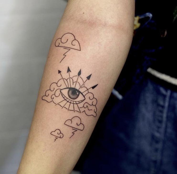 eye placed on clouds with 4 arrows tattoo design female forearm