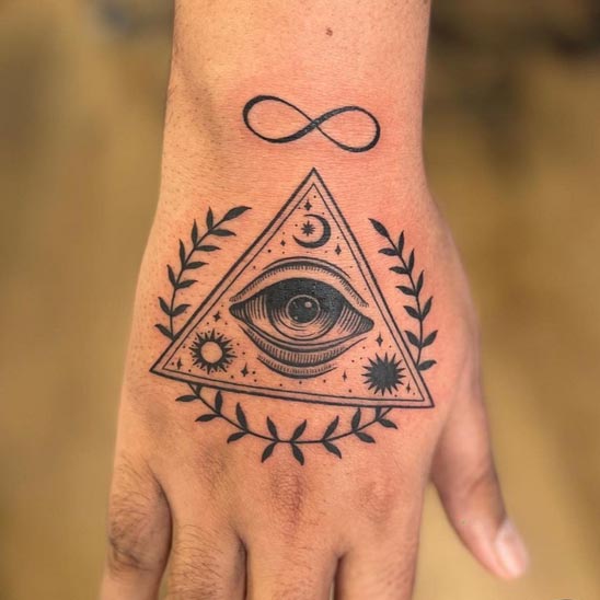 eye sun moon in triangle with laurel wreath and infinity at above tattoo design male hand