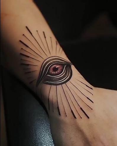 freehand eye with lines around it depicting sun rays tattoo male wrist