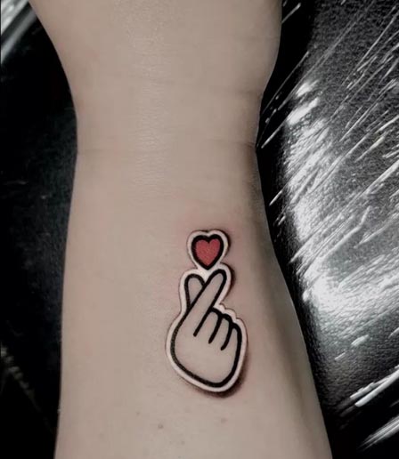 hand heart sticker minimalist tattoo female forearm