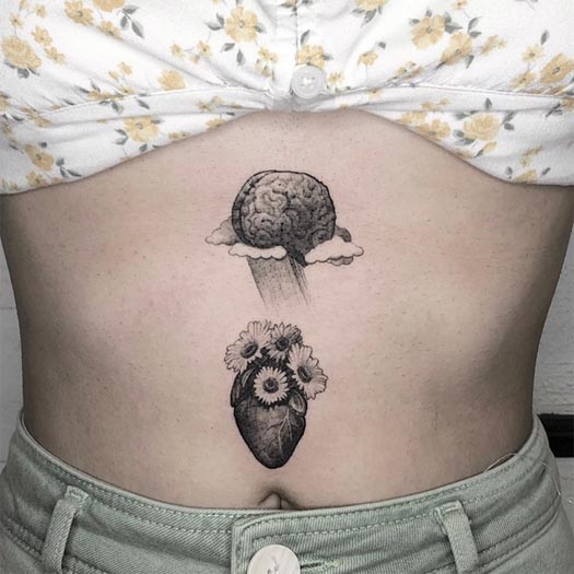 heart on clouds below brain having flowers tattoo female stomach