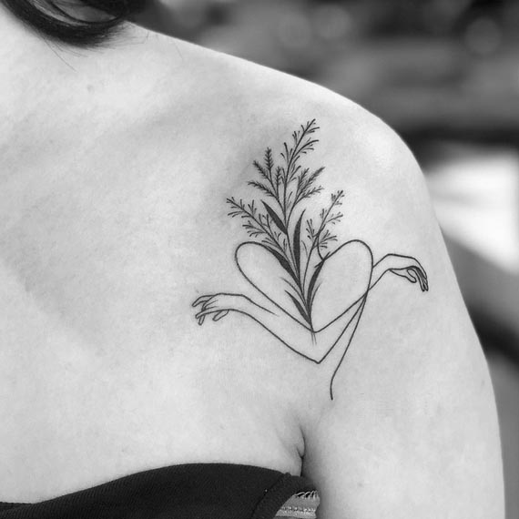 leaves above heart shaped girl arms expressing self love tattoo design female shoulder