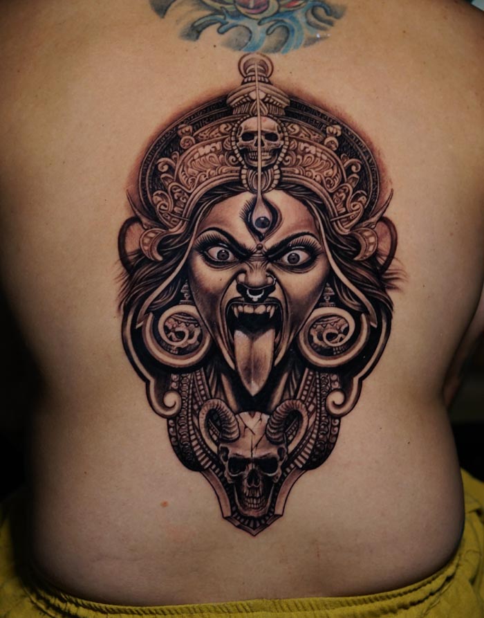 maa kali head and skull with horn tattoo on male back black and grey