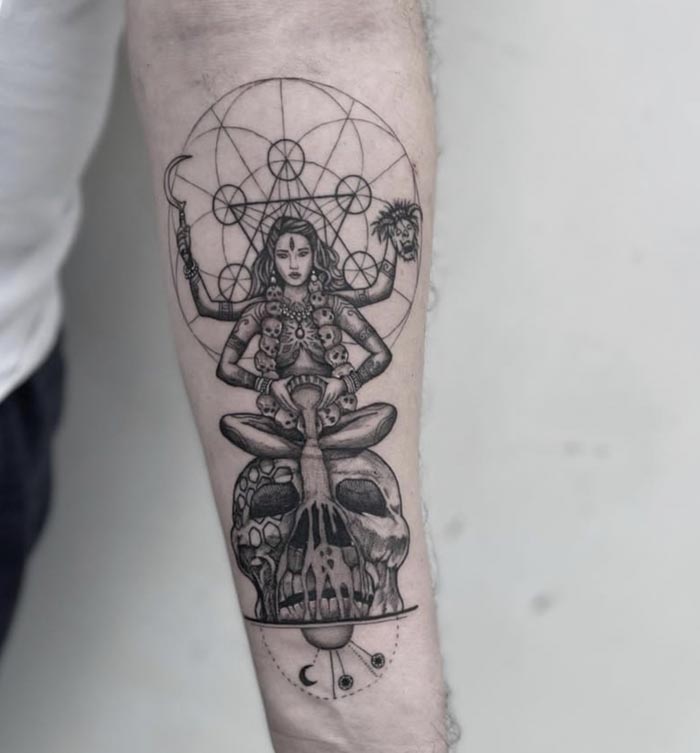 maa kali sitting on skull and pouring blood with geometric background tattoo male forearm