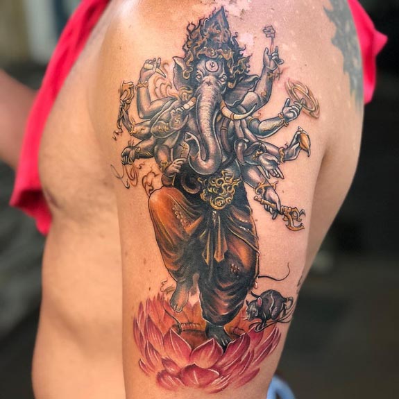 ganesha standing on lotus flower with mouse tattoo design on male bicep