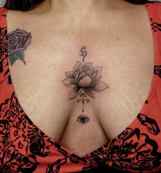 lotus flower om above evil eye below tattoo female sternum