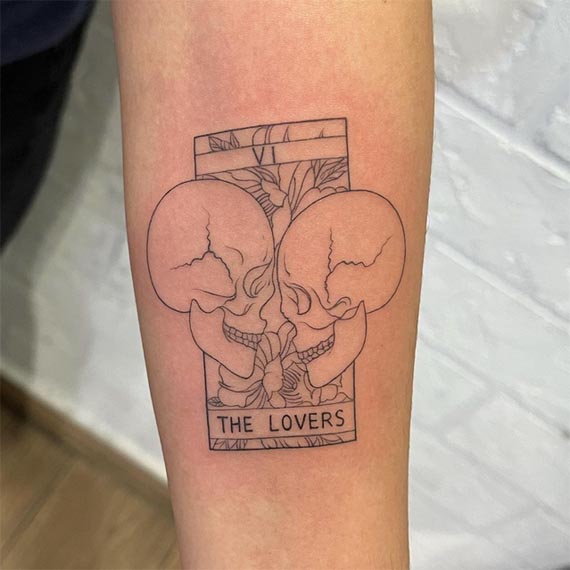 lovers 2 skulls facing each other tattoo female forearm