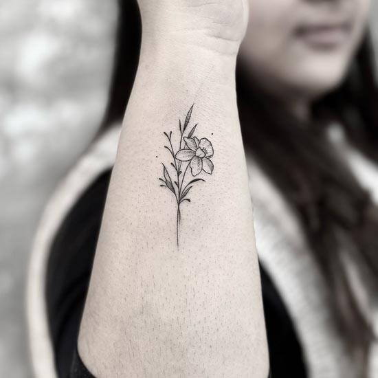 minimalist daffodil fine line tattoo design female hand forearm