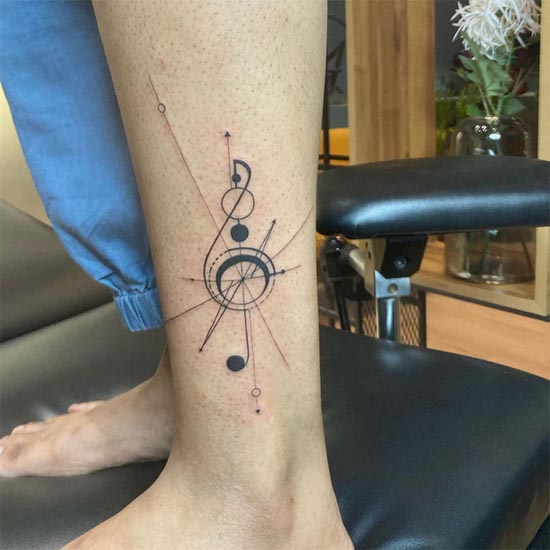 treble clef geometric linework tattoo female leg