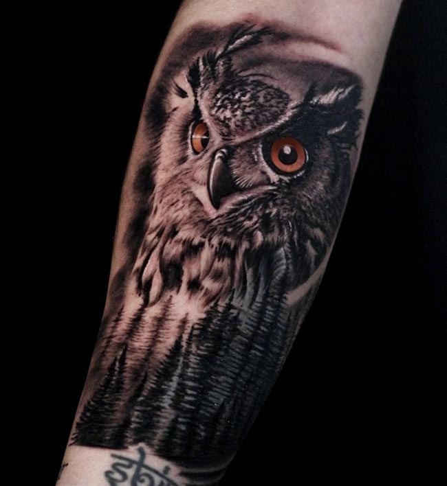 big owl head below jungle with trees tattoo male forearm