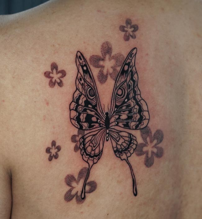butterfly having owl eyes on wings tattoo liquid flow male back