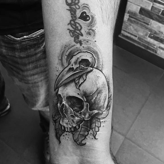 human skull bird skull on top tattoo man forearm