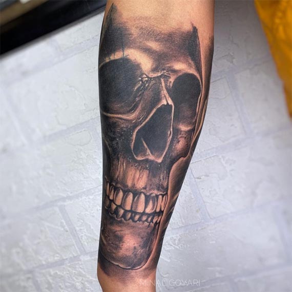 large skull tattoo design male forearm black and grey