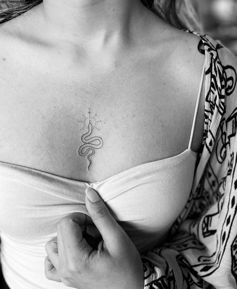 tiny snake tattoo design minimalist linework female sternum