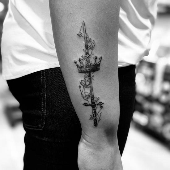 crown sword flowers tattoo design female forearm