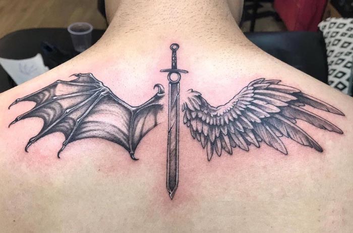 half angel half devil wings sword in center tattoo male back