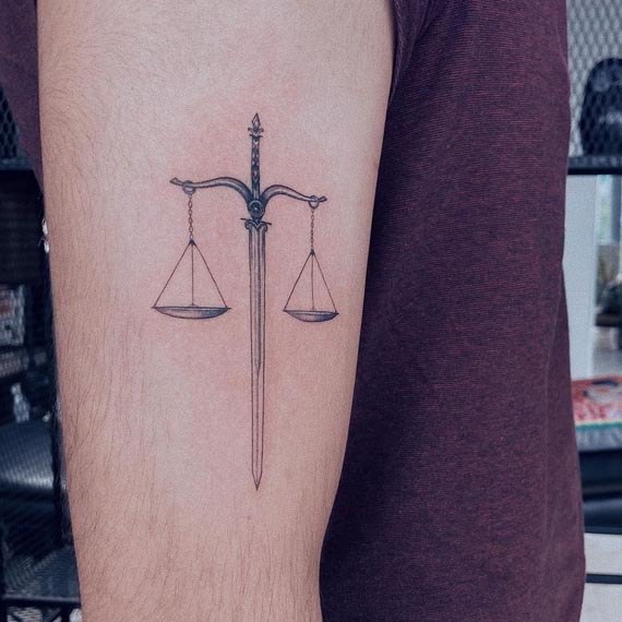 sword balance scales of justice tattoo minimalist male bicep