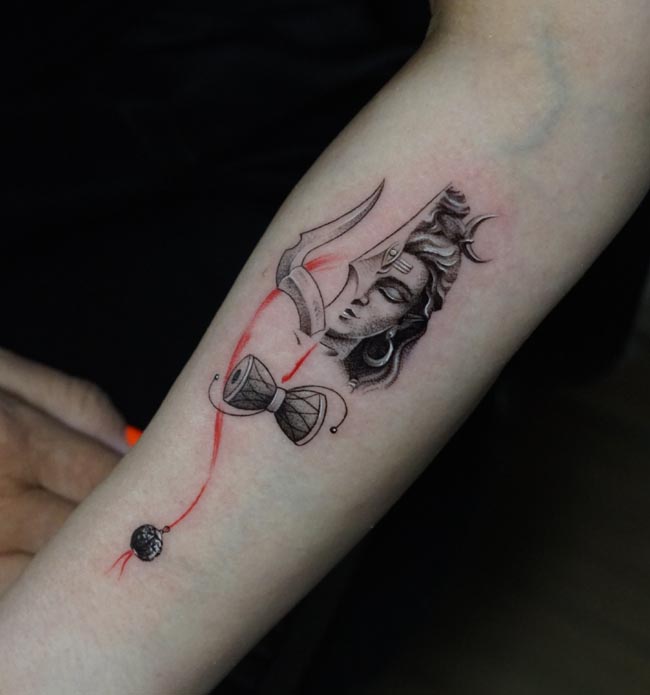 half shiva face half trishul below damru rudraksha bead tattoo female arm