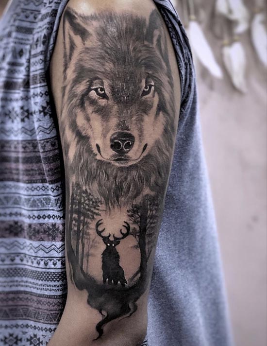 big wolf head below deer in jungle tattoo design male bicep