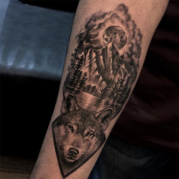 wolf head below and above forest mountain river trees tattoo male forearm