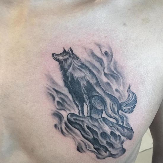 wolf standing on a rock tattoo design male chest
